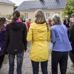 Ihmisiä selkäpäin kameraan päin, leikkivät piirileikkiä.